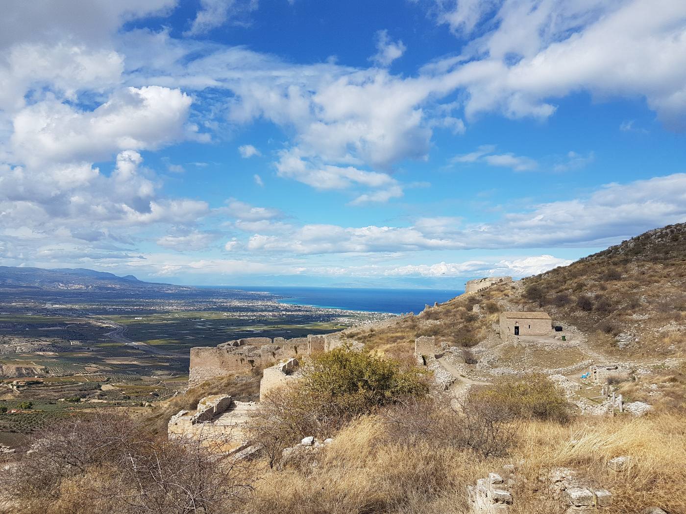 The medieval walls of Acrocorinth fortress running along the mountain ridge above the Corinthian plain and gulf