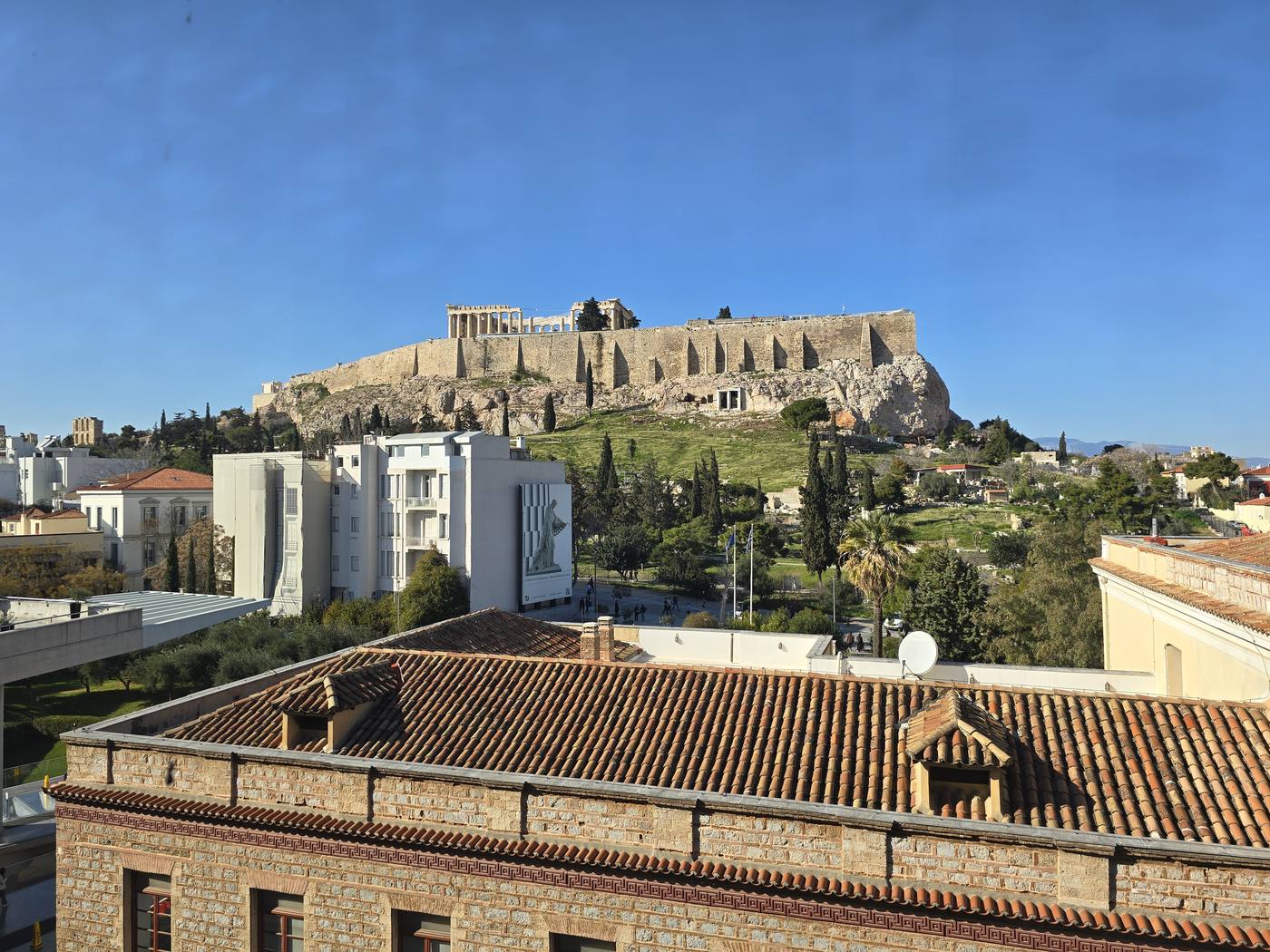 A rooftop view across Plaka's terracotta roofs to the Acropolis and Parthenon beyond
