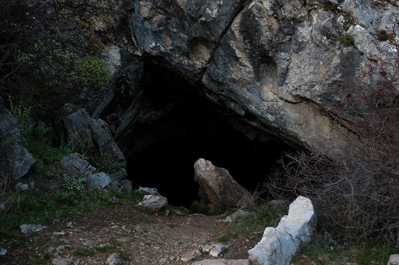 Rocky entrance to the Corycian Cave on Mount Parnassus surrounded by green vegetation