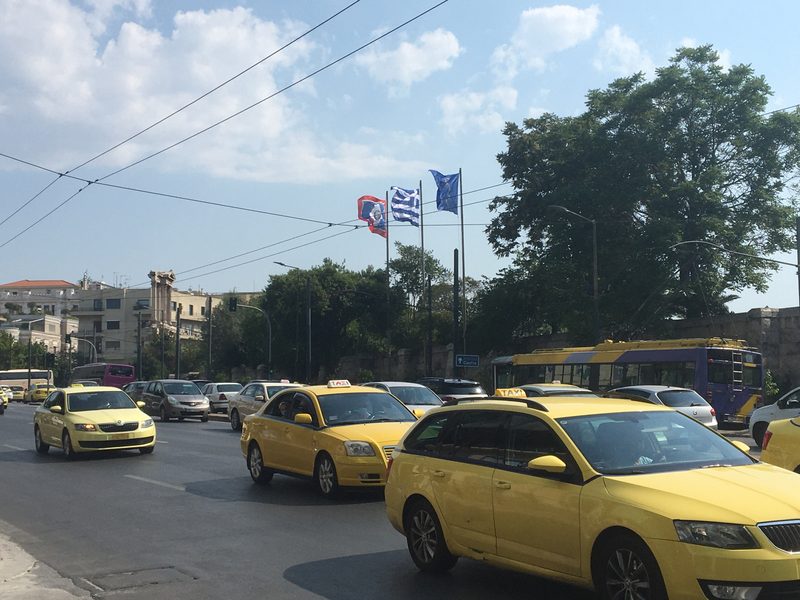 Yellow taxis lined up on a road in Athens near the Temple of Olympian Zeus