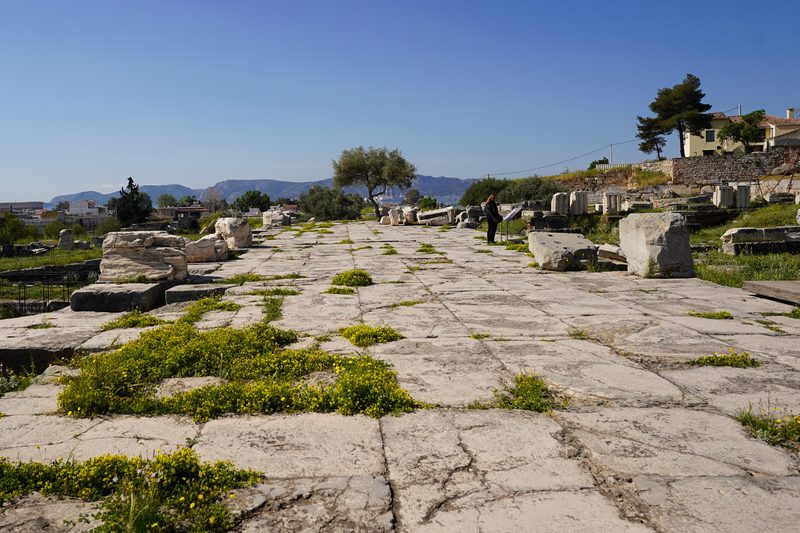 Ruins of the Telesterion at Eleusis showing ancient stone column bases and rock-cut seating steps under a clear sky