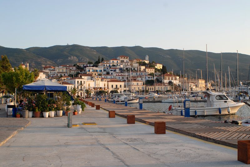Poros Town harbour with colourful buildings rising up the hillside and boats moored along the waterfront