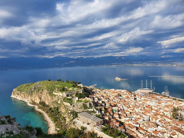 View down from Palamidi fortress over the red-roofed old town of Nafplio, with the small island castle of Bourtzi in the bay and mountains across the gulf